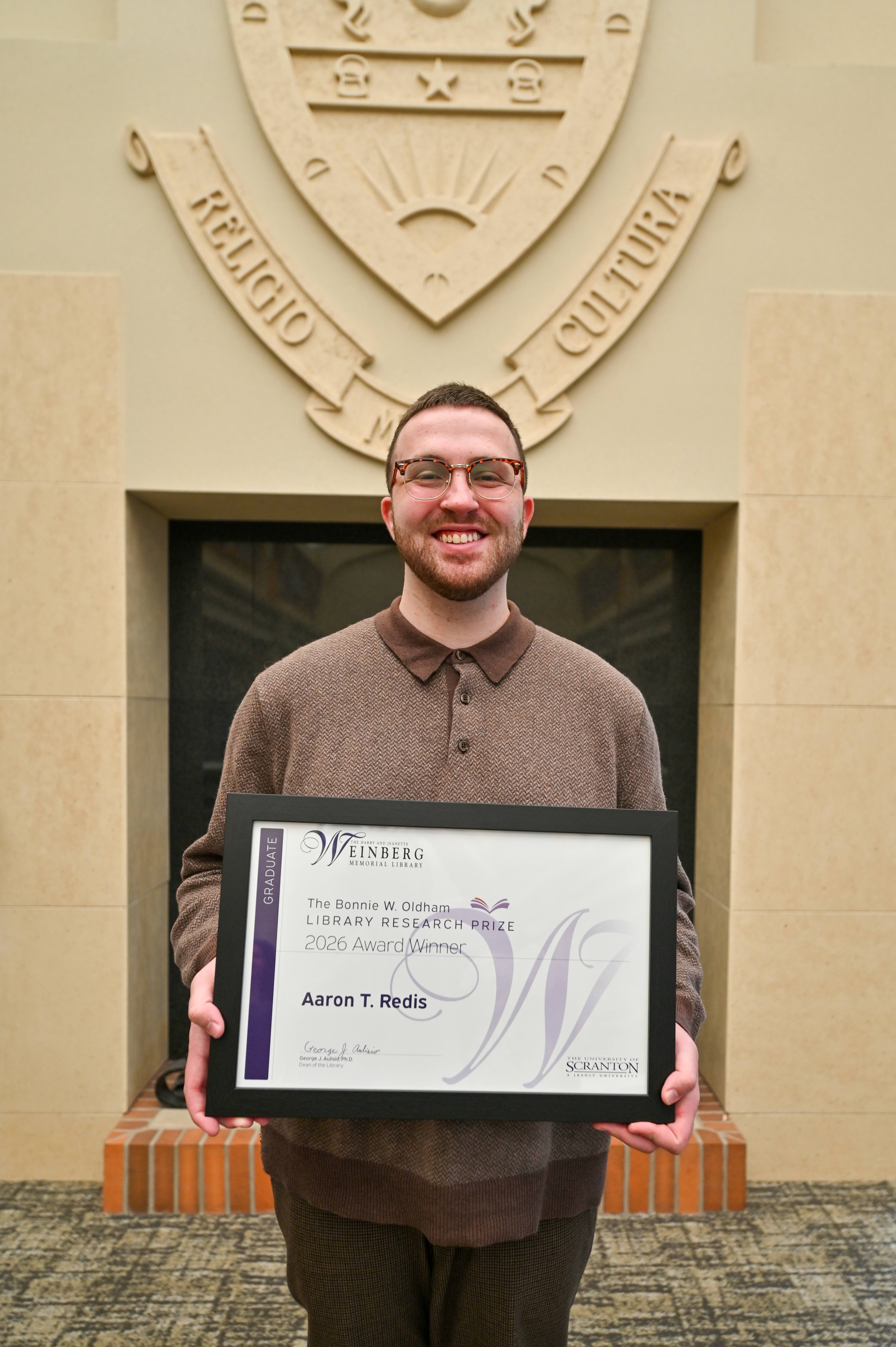 Research Prize Winner Aaron T. Redis holding framed certificate.