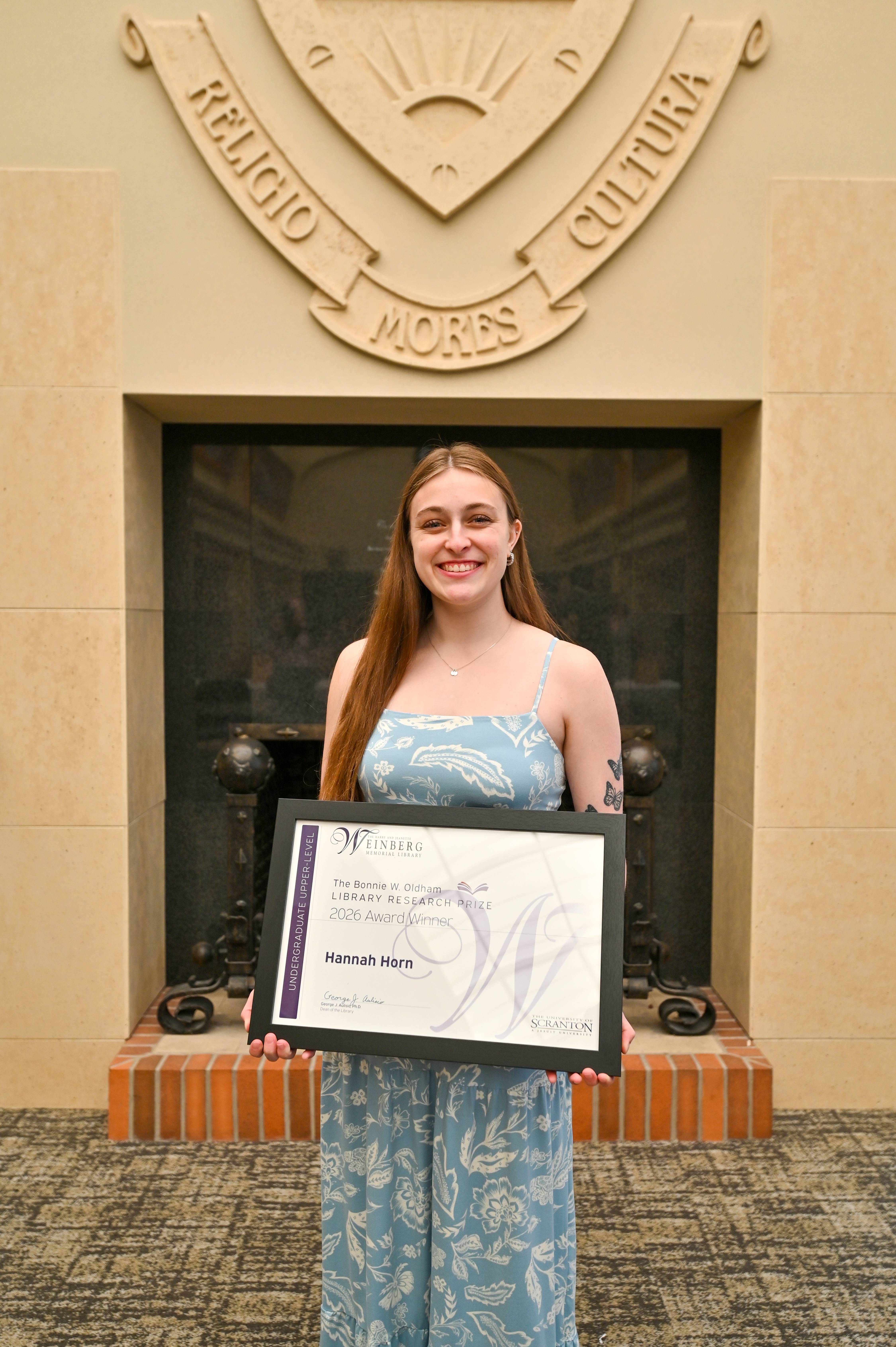 Research Prize Winner Hannah Horn holding framed certificate.