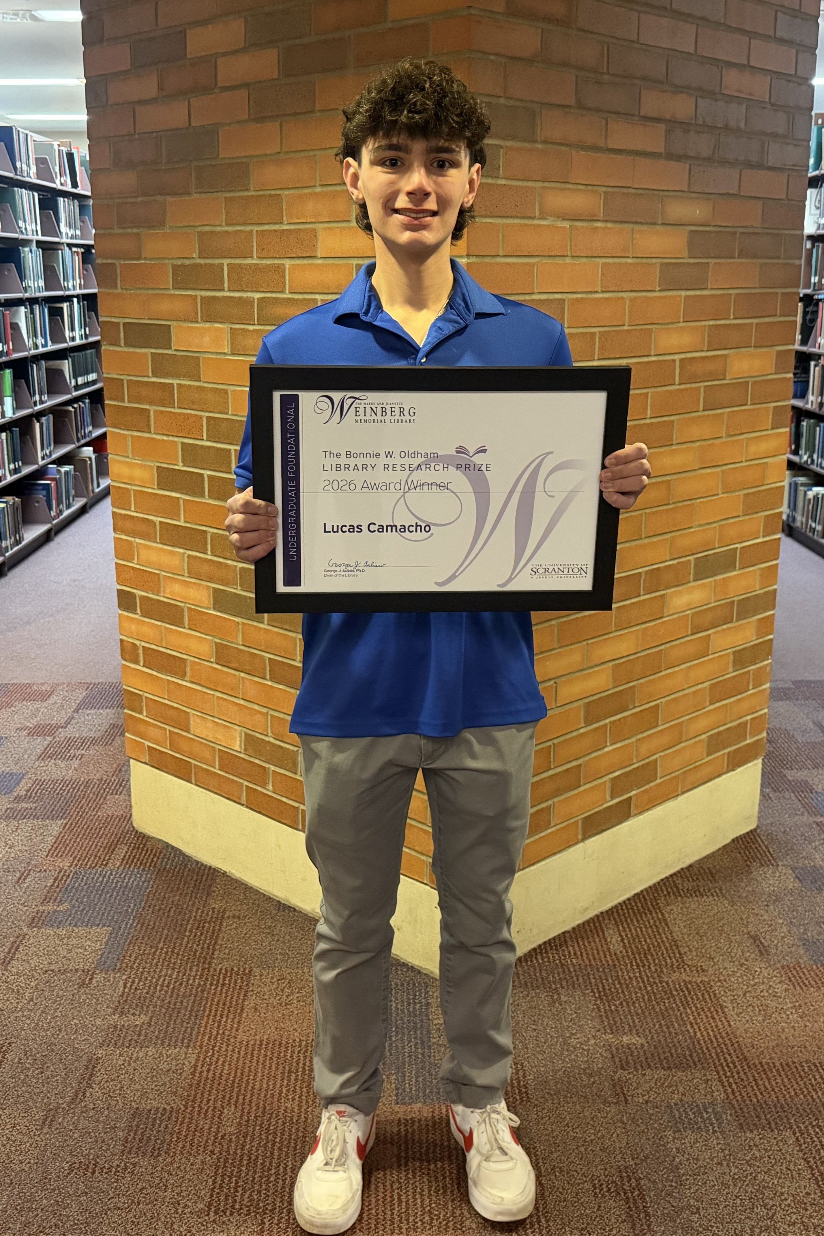 Research Prize Winner Lucas Camacho holding framed certificate.
